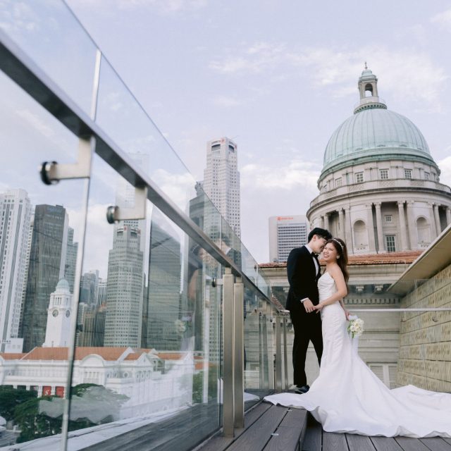 couple standing at National Gallery, overlooking singapore skyline. bride wearing a long mermaid gown, groom is in the suit.